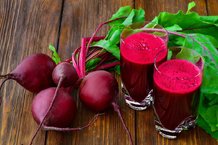 Glass of fresh beetroot juice with bets on wooden table